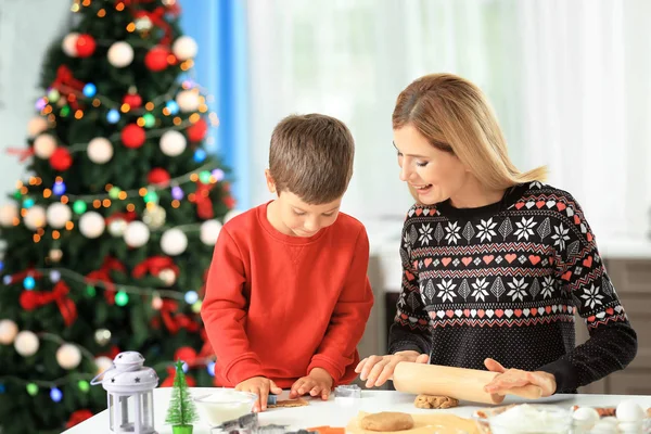 Mujer joven preparando galletas de Navidad con su hijo pequeño en la cocina — Foto de Stock