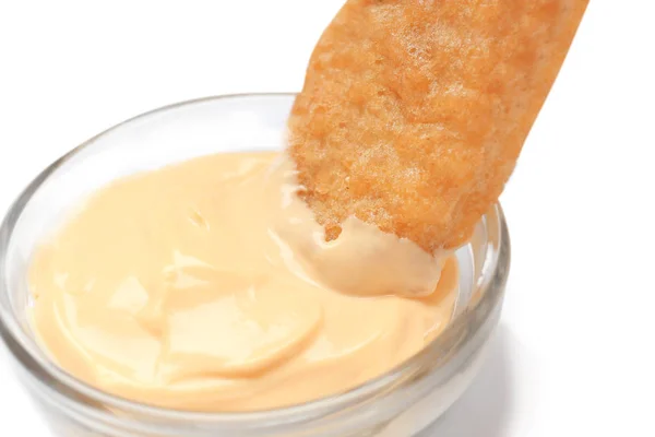 Dipping tasty nugget in small bowl with sauce for chicken on white background, closeup — Stock Photo, Image