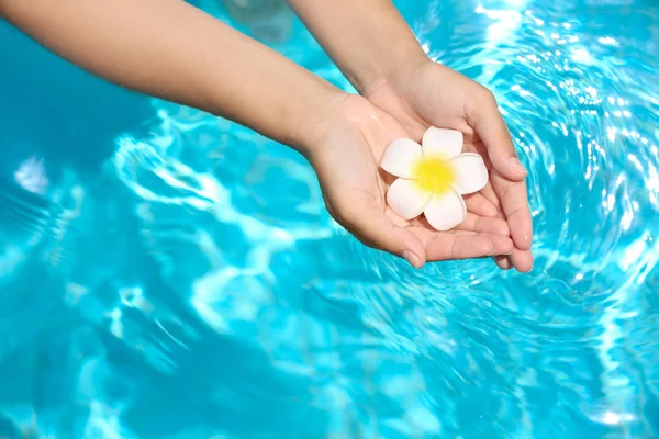 Ung kvinna hålla blomma över Blå rent vatten i poolen. Spa-konceptet — Stockfoto