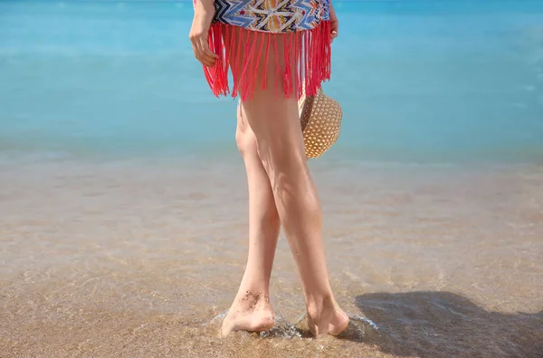 Las piernas de la hermosa mujer joven en la playa de mar — Foto de Stock