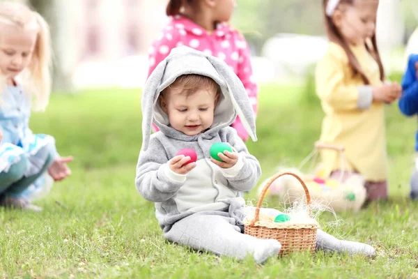 Menino bonito com cesta na grama verde no parque. Conceito de caça ao ovo de Páscoa — Fotografia de Stock