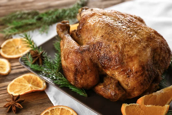 Sabroso pavo asado entero con rodajas de naranja y ramas de coníferas en la mesa — Foto de Stock