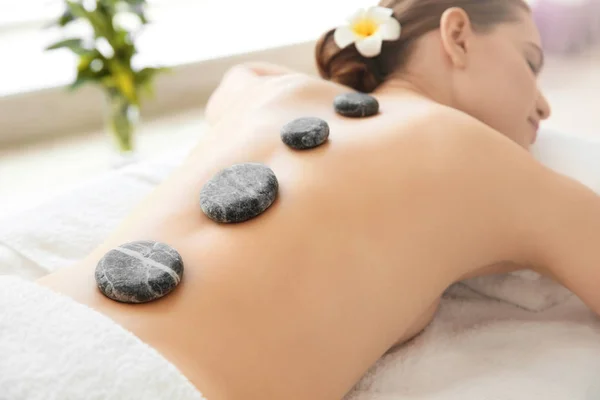 Młoda piękna kobieta o masaż kamieniami, masaż w salonie spa — Zdjęcie stockowe