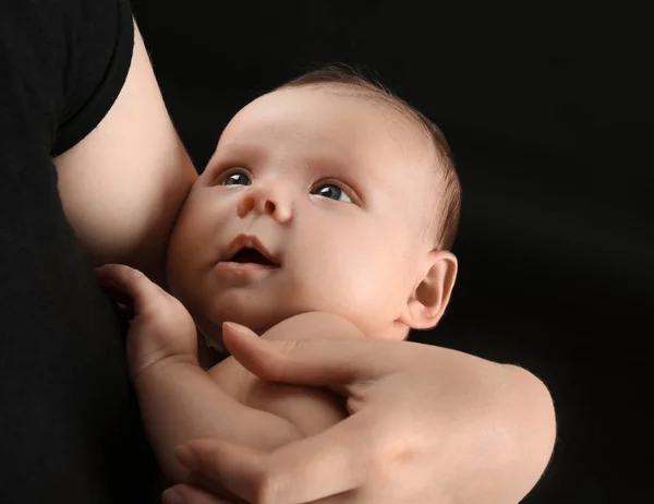 Matka trzyma noworodka na czarnym tle, zbliżenie — Zdjęcie stockowe