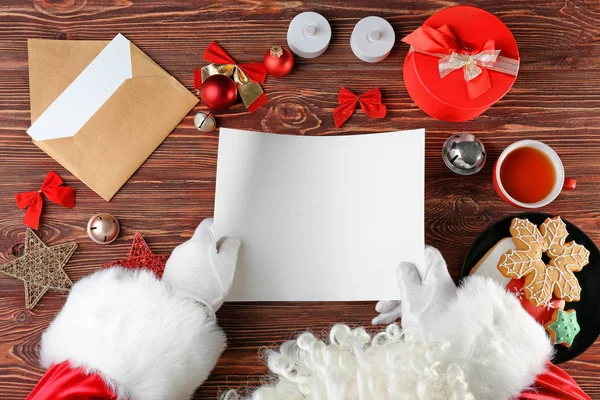 Authentieke Santa Claus houden van papieren blad aan houten tafel — Stockfoto