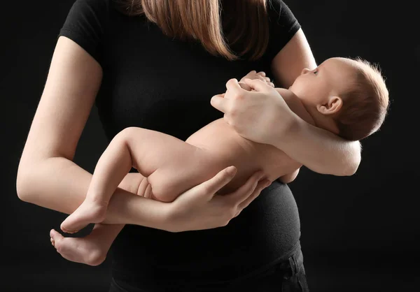 Matka trzyma noworodka na czarnym tle, zbliżenie — Zdjęcie stockowe