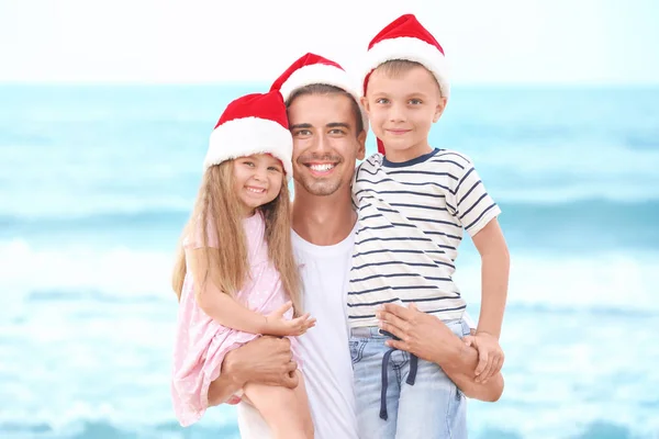 年轻的父亲在海滩上有可爱的孩子。圣诞概念 — 图库照片