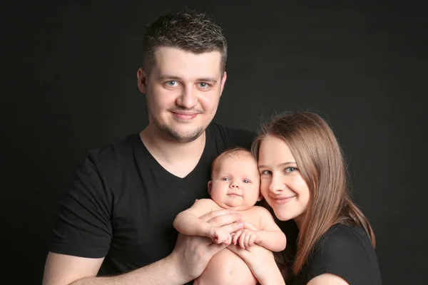 Mutlu genç aile siyah arka plan üzerine yeni doğan holding — Stok fotoğraf