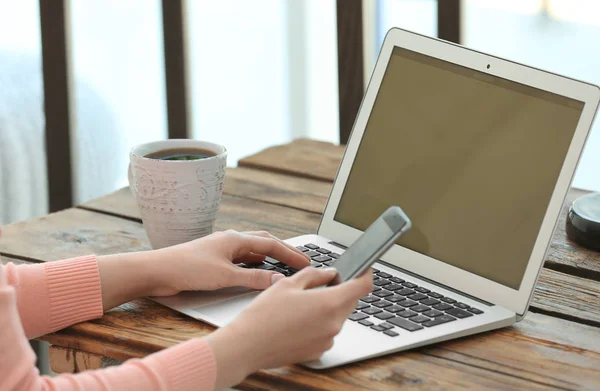 Jovem com laptop e telefone à mesa — Fotografia de Stock