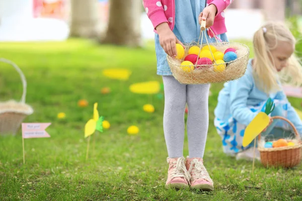 Meisje met mandje met kleurrijke eitjes in park. Pasen hunt concept — Stockfoto