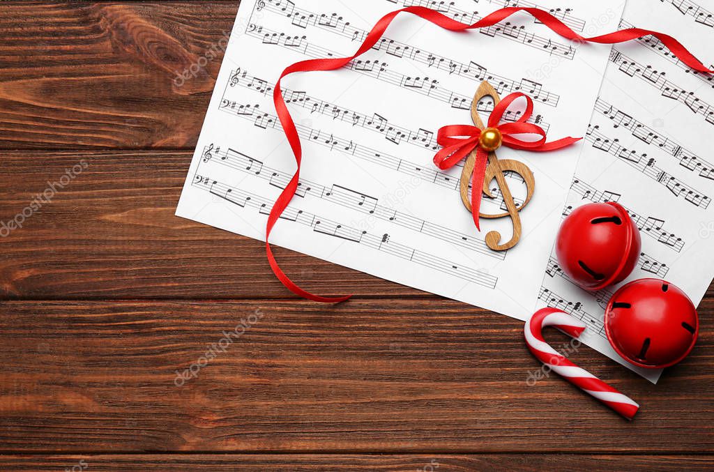 Beautiful composition with decorations and music sheets on wooden background. Christmas songs concept