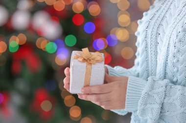 Bulanık Noel ışıklarına karşı hediye kutusu tutan kadın.