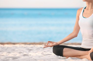 Deniz tatil köyünde yoga yapan güzel genç bir kadın.