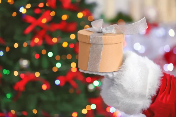 Papai Noel segurando caixa de presente contra luzes de Natal borradas — Fotografia de Stock