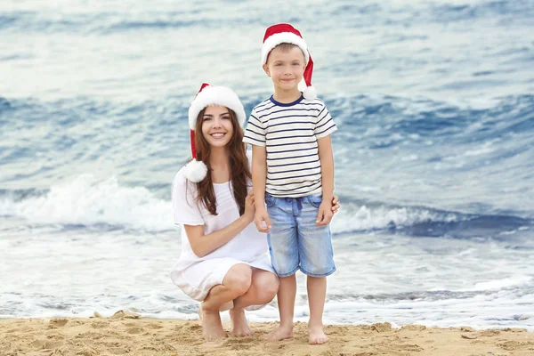 Jovem mãe com menino bonito na praia. Conceito de Natal — Fotografia de Stock