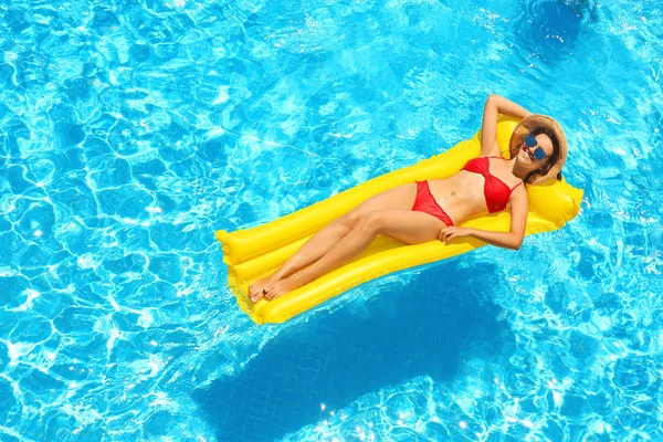 Schönes junges Mädchen entspannt sich auf aufblasbarer Matratze im blauen Schwimmbad — Stockfoto