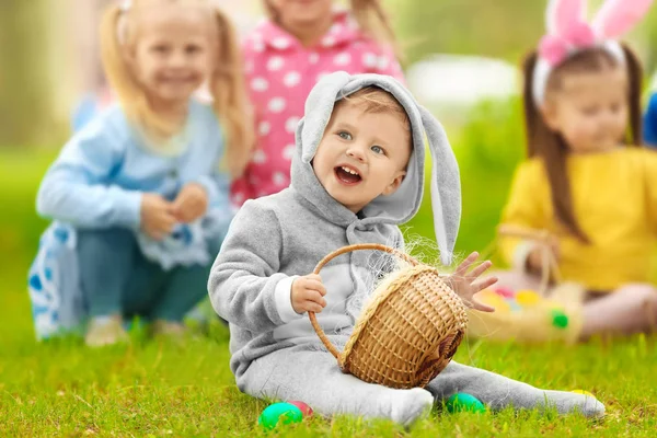 Ładny mały chłopiec z koszem na zielonej trawie w parku. Easter egg hunt koncepcja — Zdjęcie stockowe