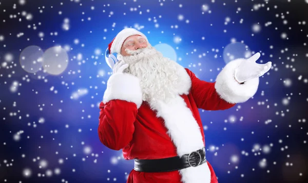 Kerstman met koptelefoon luisteren naar kerst muziek en sneeuw effect op kleur achtergrond — Stockfoto