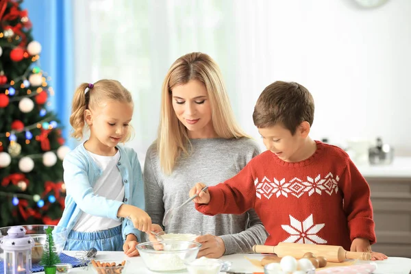 Jonge vrouw voorbereiding van kerstkoekjes met kleine kinderen in de keuken — Stockfoto