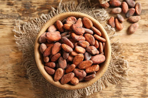 Kom met aromatische stukjes cacaobonen op houten tafel — Stockfoto
