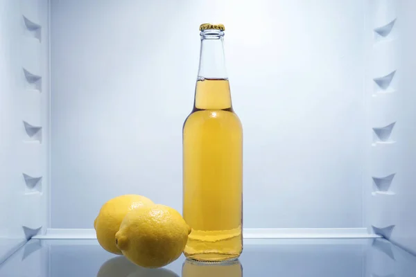 Bottle of lemonade with fresh lemons in fridge — Stock Photo, Image