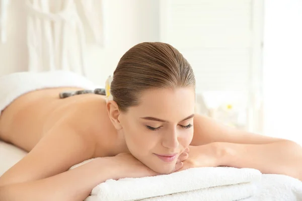 Mooie jongedame met stenen massage in de spa salon — Stockfoto
