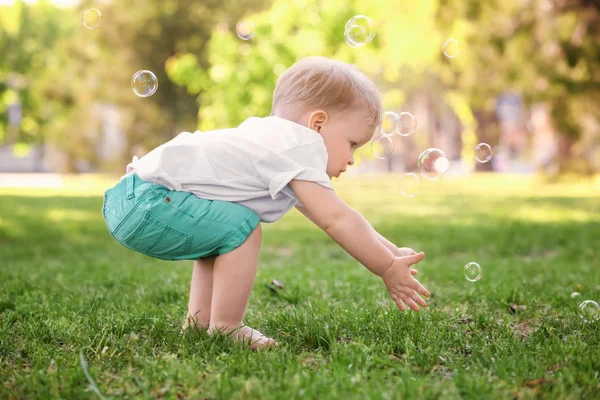 Bayi laki-laki lucu berjalan di taman hijau pada hari yang cerah — Stok Foto