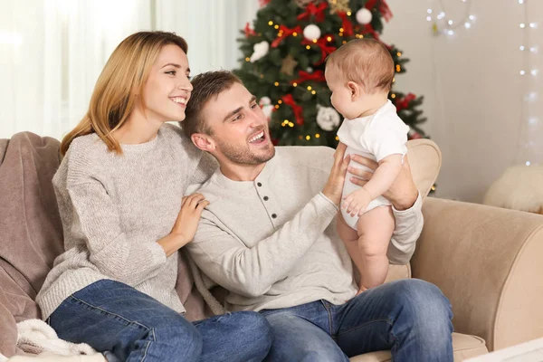 Glückliche Eltern mit Baby im weihnachtlich dekorierten Zimmer — Stockfoto