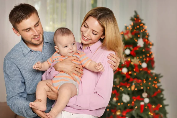 Glückliche Eltern mit Baby im weihnachtlich dekorierten Zimmer — Stockfoto