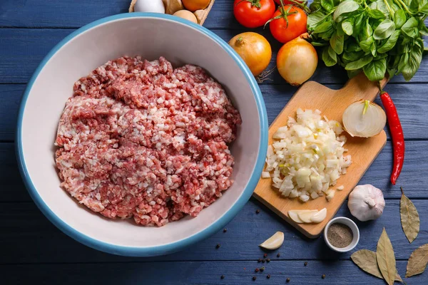 Bowl with ground turkey and ingredients for delicious meatloaf on wooden table