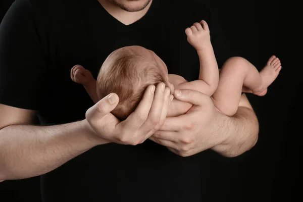 Ojciec trzymający noworodka na czarnym tle — Zdjęcie stockowe