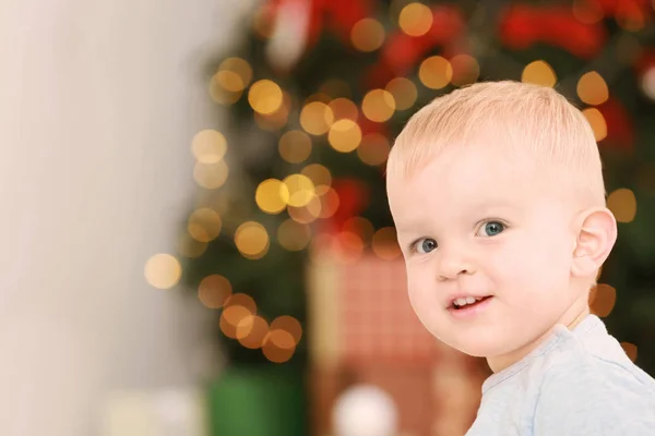 Niedliches kleines Baby gegen defokussiertes Licht. Weihnachtskonzept — Stockfoto