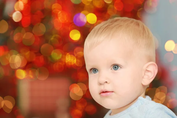 Niedliches kleines Baby gegen defokussiertes Licht. Weihnachtskonzept — Stockfoto