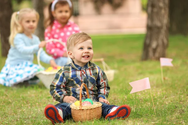 Ładny mały chłopiec z koszem na zielonej trawie w parku. Easter egg hunt koncepcja — Zdjęcie stockowe