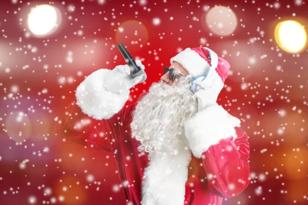 Weihnachtsmann singt Lieder auf farbigem Hintergrund. Weihnachts- und Neujahrsmusik — Stockfoto