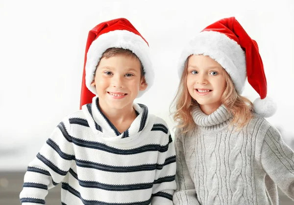 Crianças em Papai Noel chapéus no fundo claro — Fotografia de Stock
