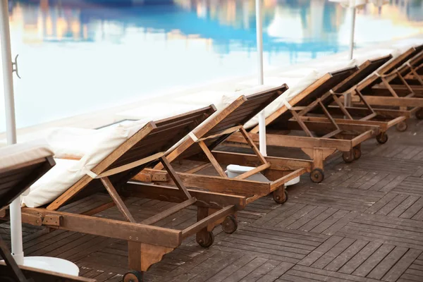 Tumbonas vacías cerca de la piscina en un hotel de lujo —  Fotos de Stock
