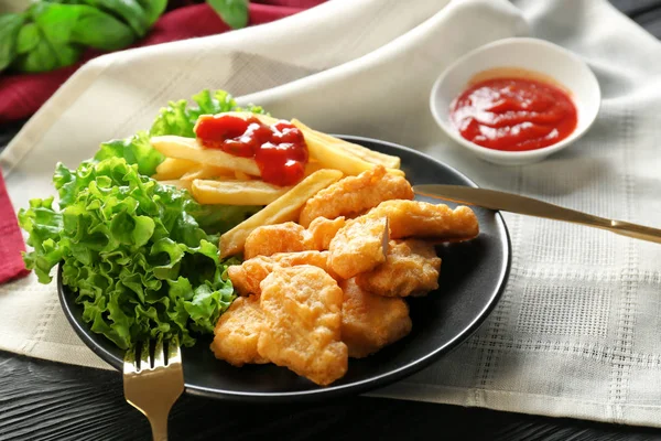 Tasty nuggets, french fries and small bowl with sauce for chicken on table — Stock Photo, Image