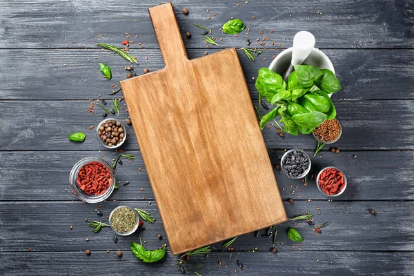 Composition with cutting board, spices and herbs on wooden background — Stock Photo, Image