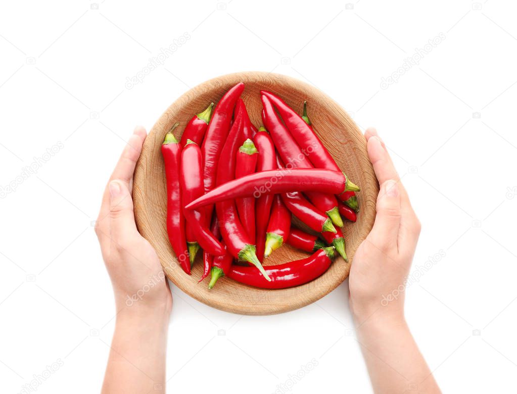 Woman's hands holding wooden plate with red chili peppers isolated on white