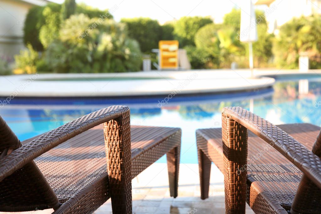 Comfortable sun loungers near swimming pool at resort