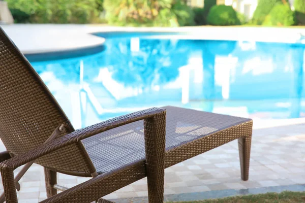 Comfortable sun lounger near swimming pool at resort — Stock Photo, Image