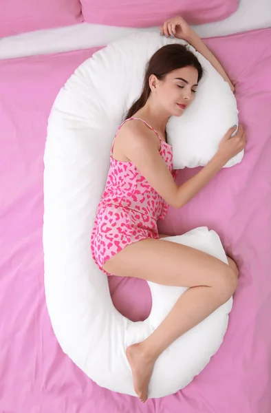 Jovem bela mulher dormindo no corpo travesseiro na cama — Fotografia de Stock