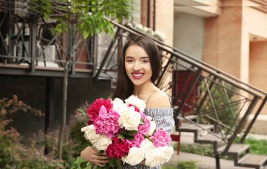Sokakta duran peonies güzel buket olan neşeli kadın