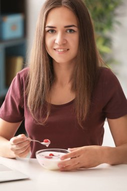 Genç kadın masada yoğurt yeme