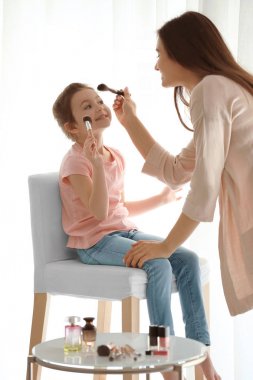 Genç kadın ve küçük kızı evde makyaj uygulamak