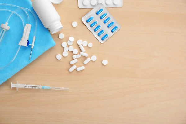 Spritze mit Pillen und Katheter auf Holztisch — Stockfoto