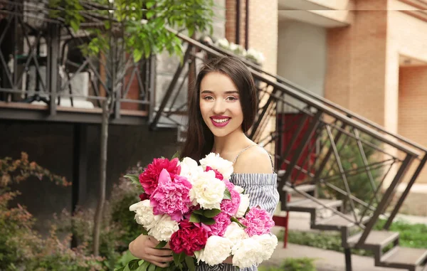 Sokakta duran peonies güzel buket olan neşeli kadın