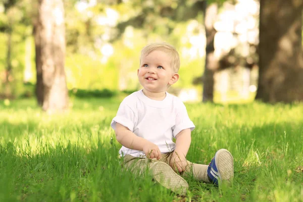 Ładny chłopczyk z mniszka lekarskiego w zielonym parku na słoneczny dzień — Zdjęcie stockowe