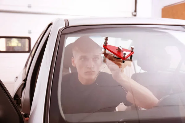 Специалист, фиксирующий трещину на лобовом стекле автомобиля в ремонтной мастерской — стоковое фото